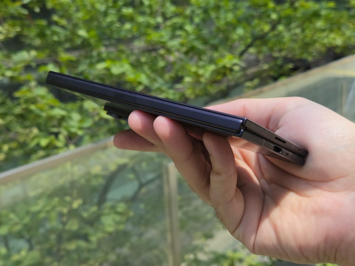 Samsung Galaxy Z Fold8 Ultra plegado visto de perfil, sostenido con una mano, mostrando su diseño fino, la bisagra y el puerto USB-C.